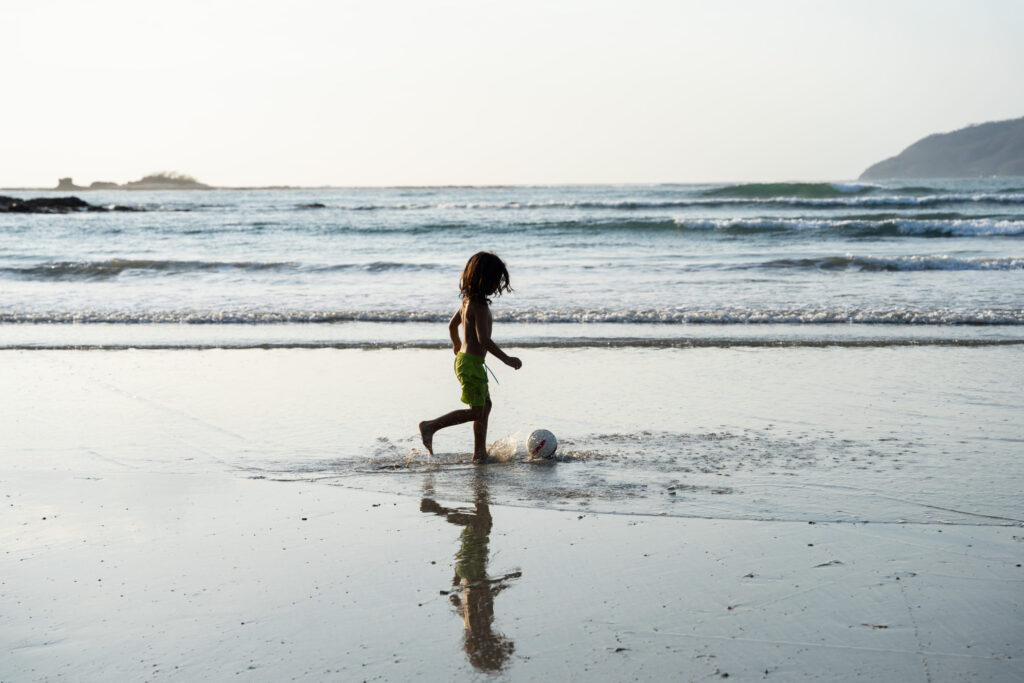 Child playing in the waves at sunset on a Guanacaste beach